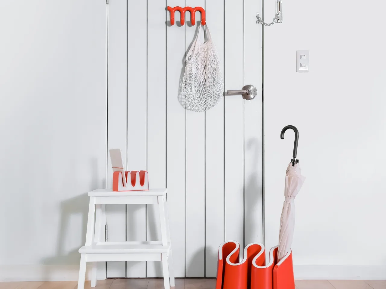 Gancho de pared con forma de subrayado rojo ondulado sosteniendo un juego de llaves