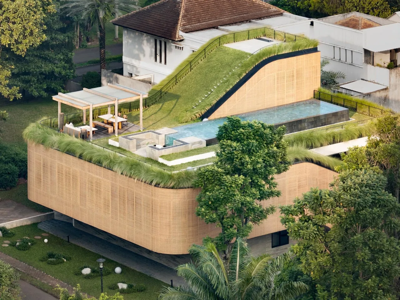 Esta casa indonesia transforma su techo inclinado en jardín, escalera y pileta en la azotea
